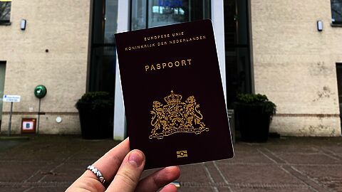 Paspoort in de hand voor deur gemeentehuis