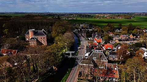 Luchtfoto van een dorp  met weilanden op de achtergrond.