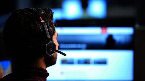 Man met headphone voor een computerscherm
